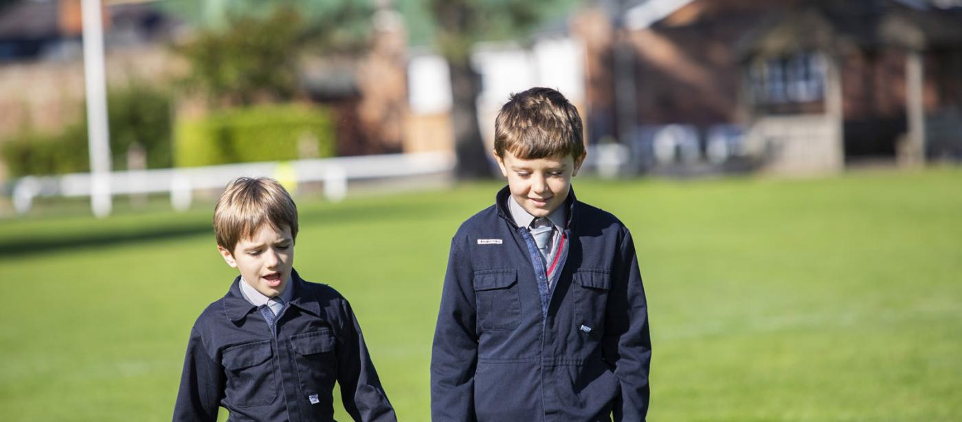 Two boys walking across the school field